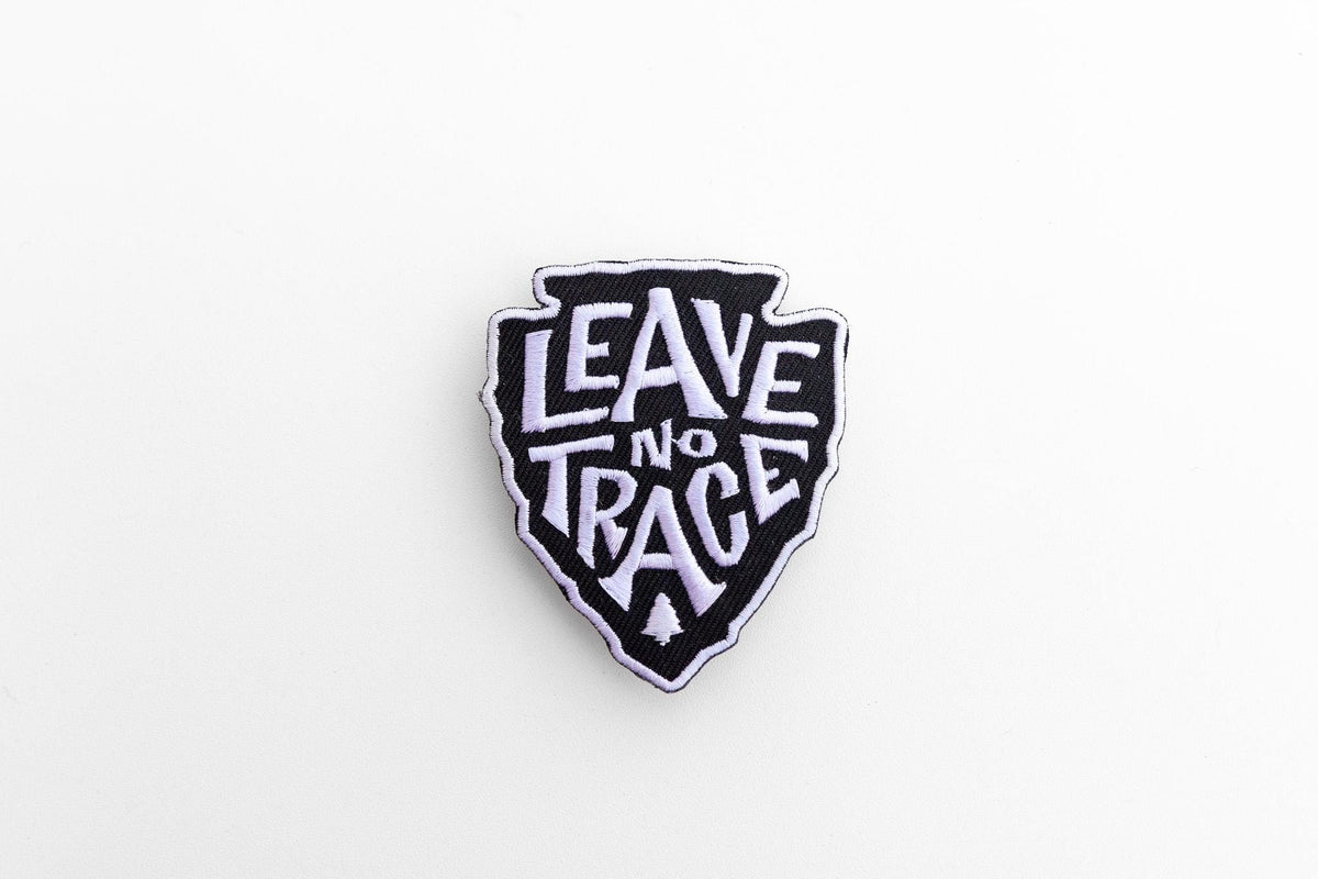 Small against a wide white background, the Leave No Trace patch shows its full arrowhead outline.