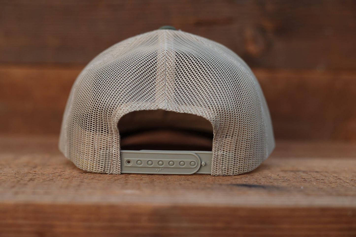 Back of the olive Olympic National Park trucker hat, tan mesh and a row of snap holes above brown wood.