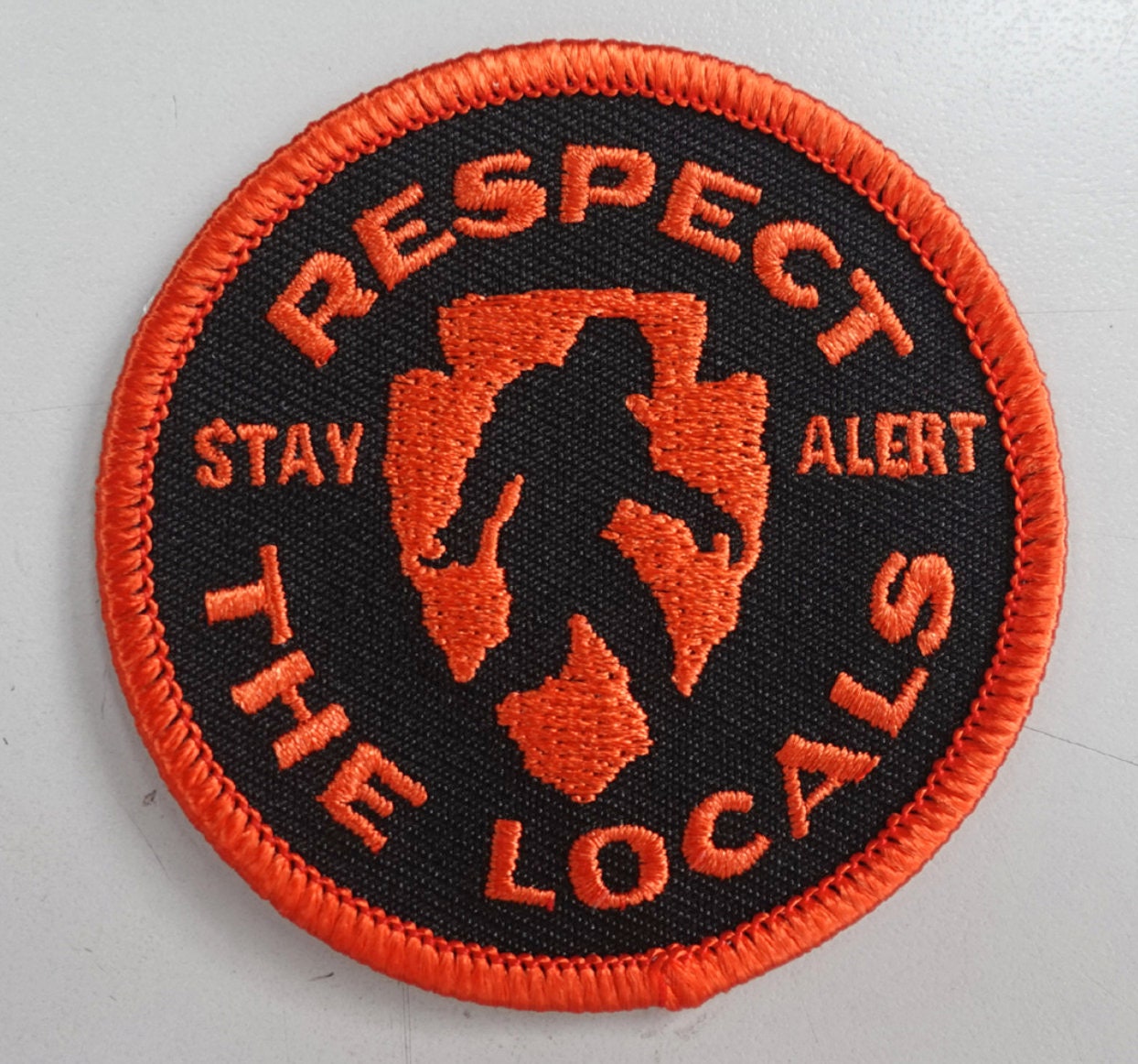 Filling the frame, the Respect the Locals patch shows its orange merrowed edge and Bigfoot silhouette up close.