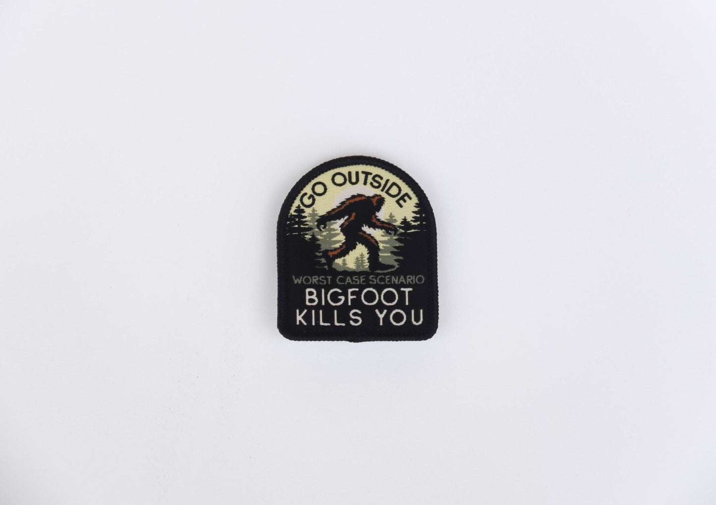 Set low against plain white, the Bigfoot Kills You embroidered patch shows tree line and walking Sasquatch.