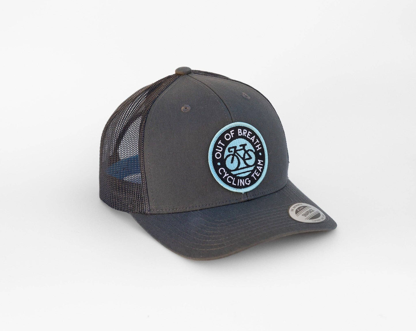 Straight on from a low angle, the grey Out of Breath Cycling Team trucker hat shows stitched patch letters.