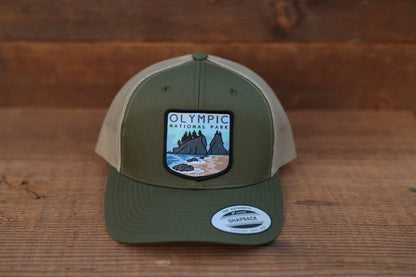 Front and centered, the green and tan Olympic National Park trucker hat still wears its snapback brim sticker.