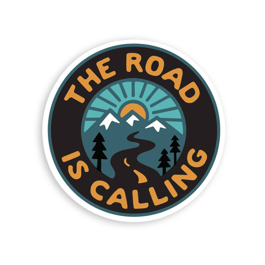 The Road is Calling sticker shows a winding road, snowy peaks and a rising sun inside a dark circle.
