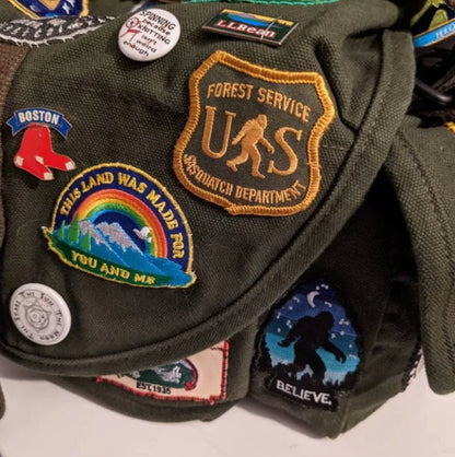 On a jacket crowded with pins and patches, the US Sasquatch Department patch takes the center spot.