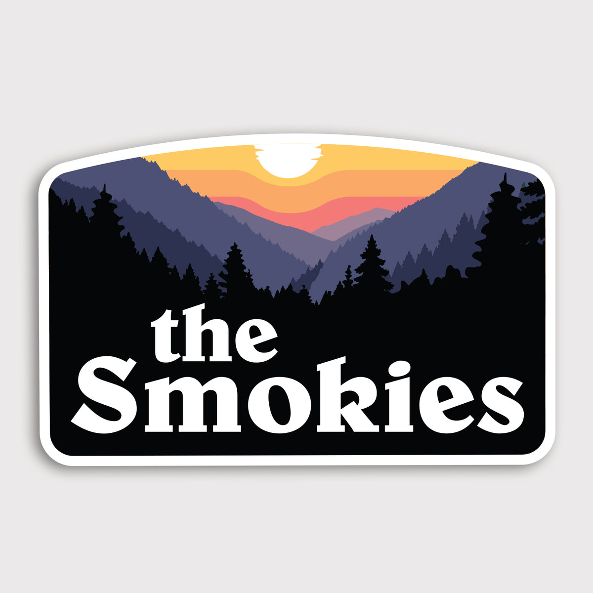 Layered mountain silhouettes glow orange and pink behind a setting sun on the arched The Smokies sticker.