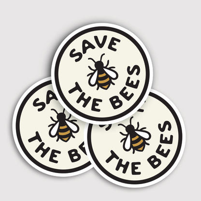 Three Save The Bees stickers overlap in a small pile, their bee icons facing different directions.