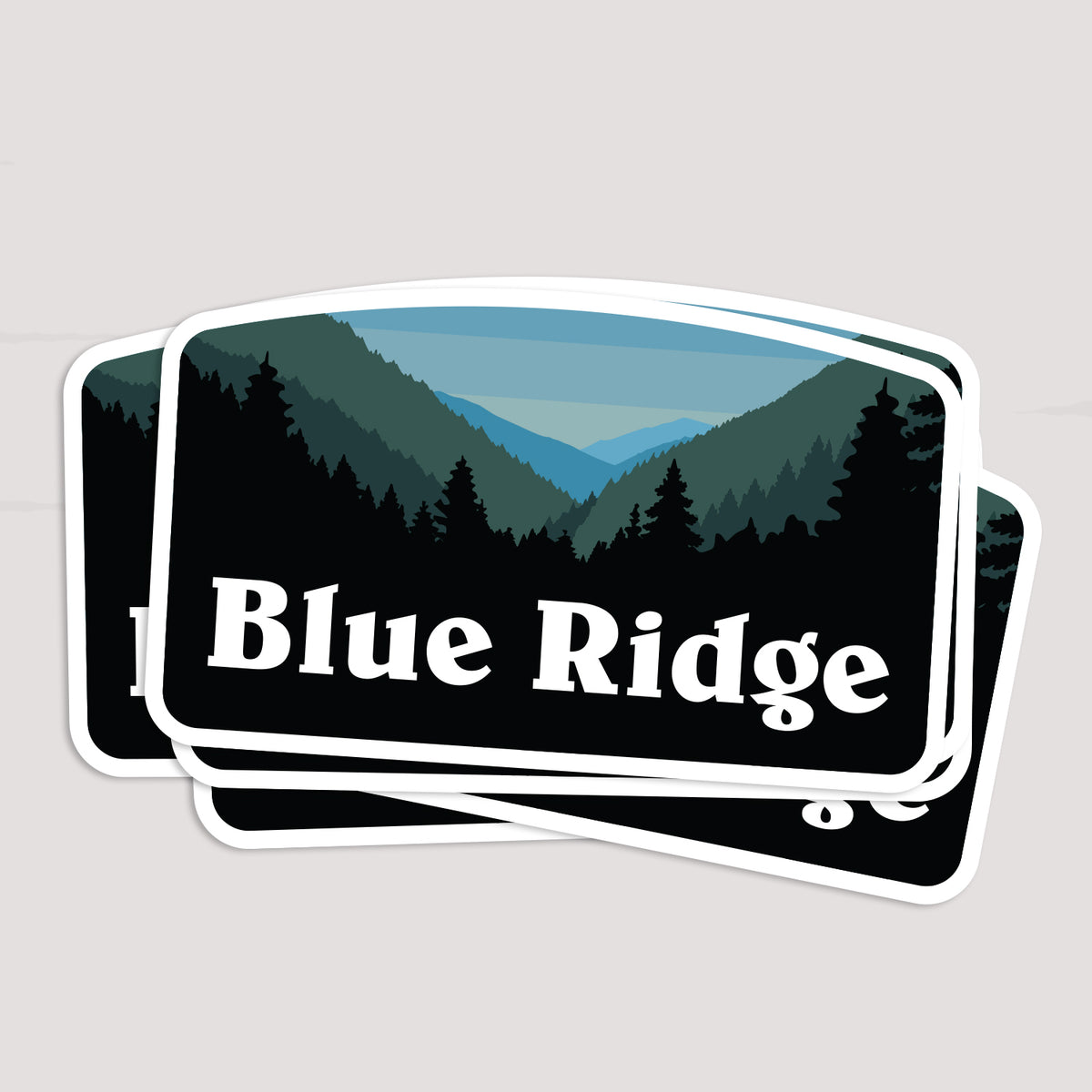 Two Blue Ridge stickers lie stacked at an angle, one partly covering the other on a plain surface.