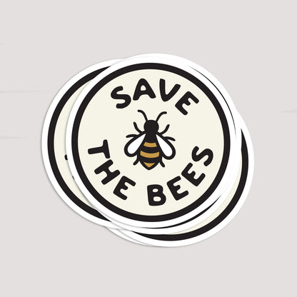Several Save The Bees stickers lie fanned in a loose stack, each round edge overlapping the next.