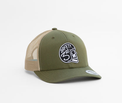 In olive green with tan mesh, the Safety 3rd Helmet trucker hat shows its white skull patch from the front.
