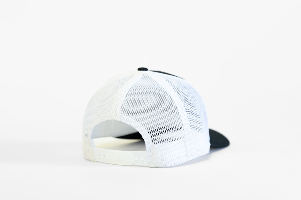 Seen from behind, the black and white Safety 3rd Helmet trucker hat shows its plastic snap adjuster.