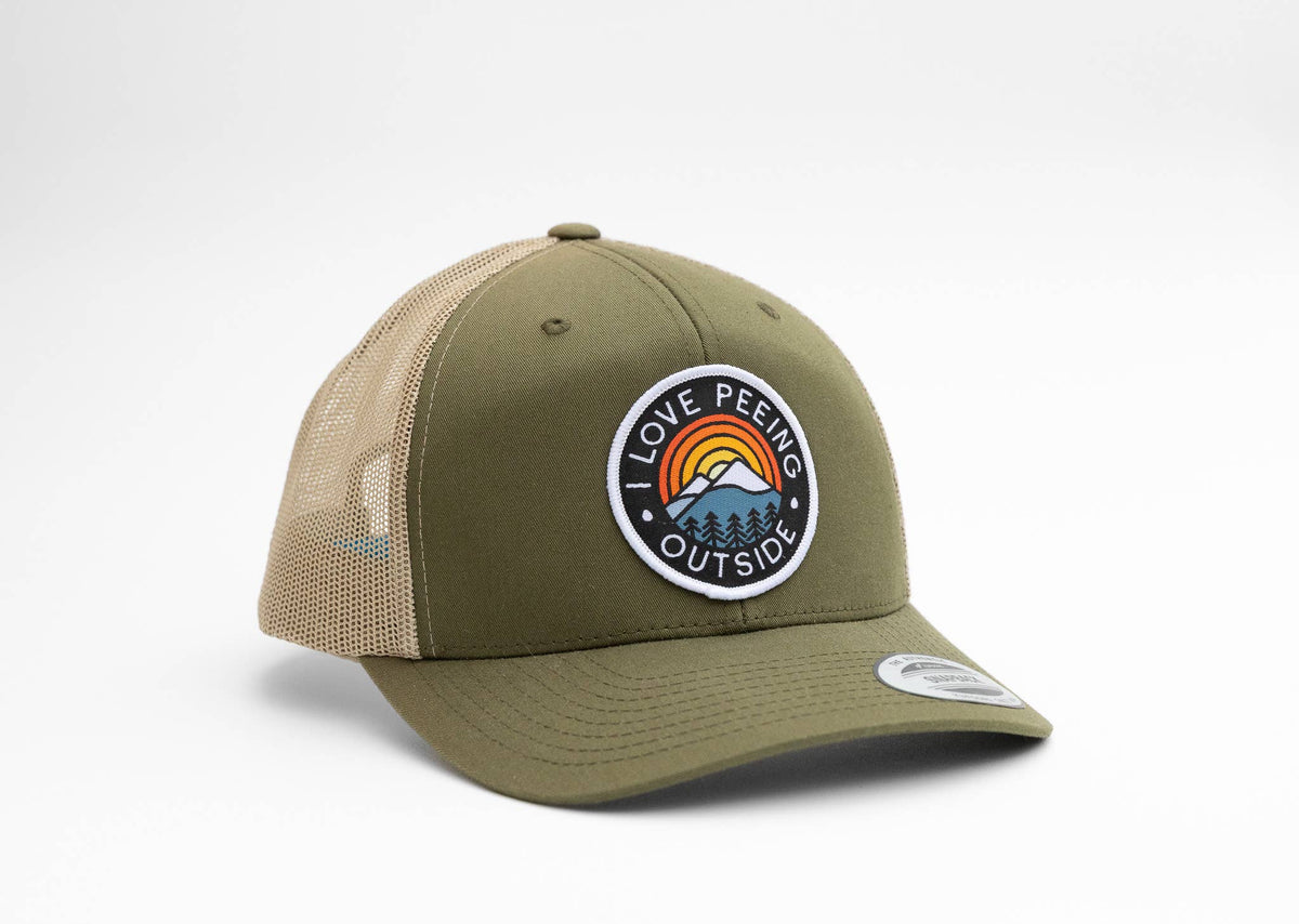 Olive green I Love Peeing Outside trucker hat angled to show its round rainbow and mountain patch on white.