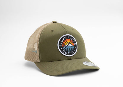 Olive green I Love Peeing Outside trucker hat angled to show its round rainbow and mountain patch on white.