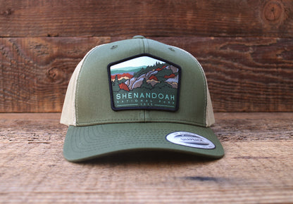 Standing on weathered planks, the olive Shenandoah National Park trucker hat faces forward with its patch centered.