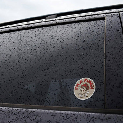 Stuck low on the rain beaded window of a black car, the I'm a Fungi sticker holds through the wet.