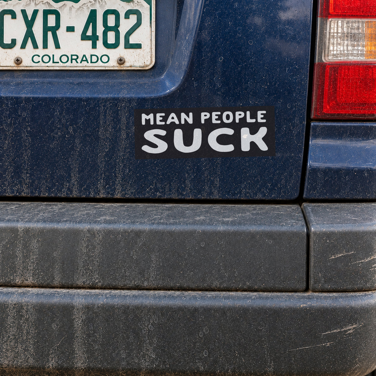 On a dusty blue bumper under a Colorado plate, the Mean People Suck sticker shows its bold white lettering.