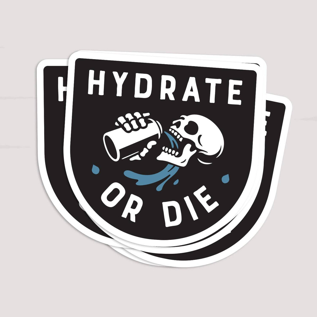 Two Hydrate or Die stickers overlap in a small stack on a pale surface.