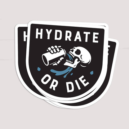 Two Hydrate or Die stickers overlap in a small stack on a pale surface.