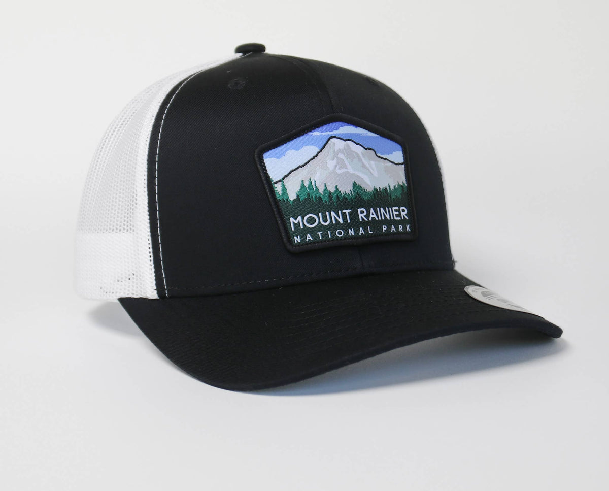 Black Mount Rainier National Park trucker hat with white mesh, patch showing pines below the summit.