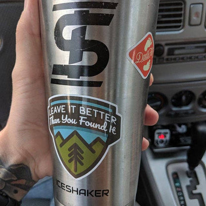 A steel Ice Shaker tumbler in a car carries the Leave It Better Than You Found It sticker.