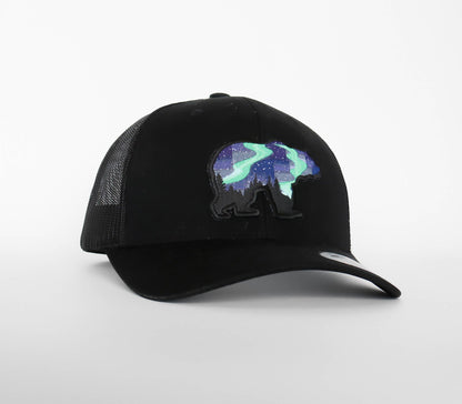 All black Northern Lights Grizzly Bear trucker hat with the aurora bear patch stitched across the front panel.