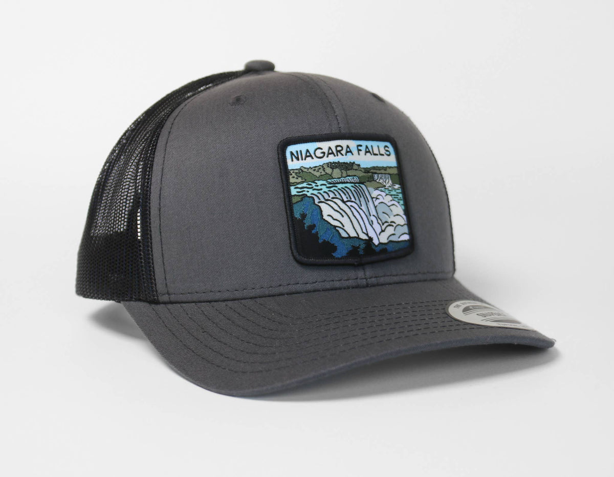 Charcoal grey Niagara Falls trucker hat with black mesh, angled to show the falls patch and curved brim.