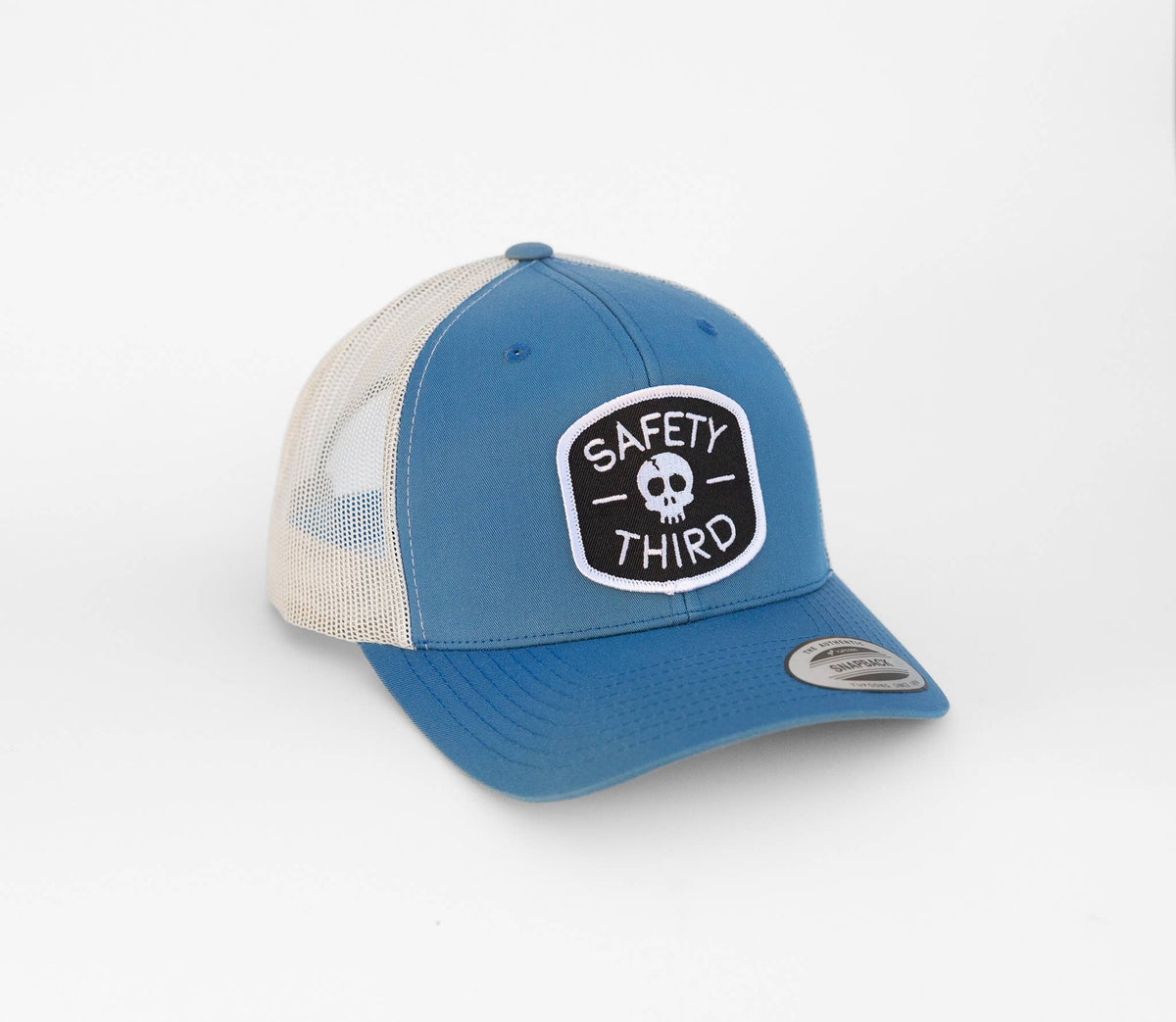 Blue crown and cream mesh meet on the Safety Third trucker hat turned three quarters toward the camera.
