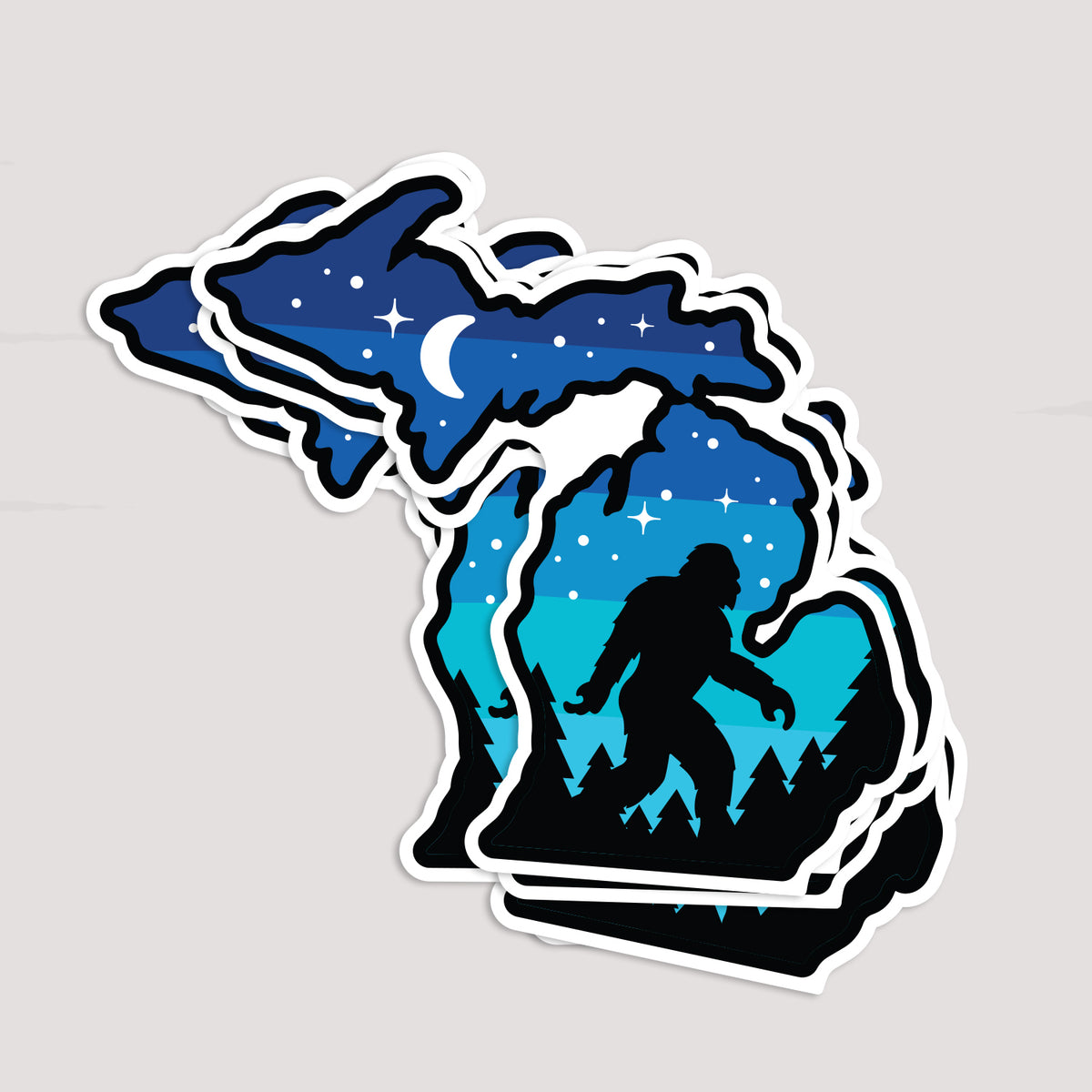 Several Michigan Sasquatch stickers are stacked together, fanning out to show repeated copies of the same design.