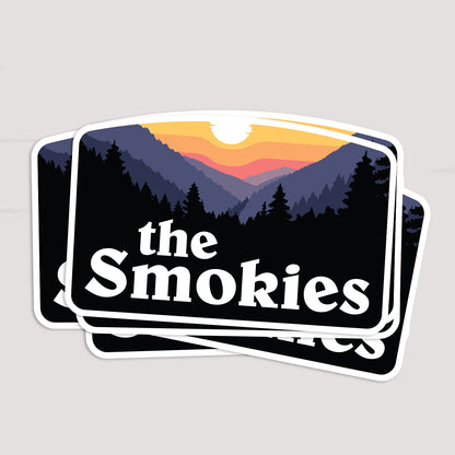 Three The Smokies stickers fan out in a stack, each showing the same sunset mountain scene.