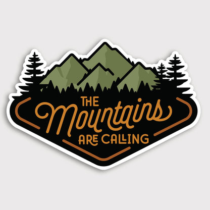 The Mountains Are Calling sticker lies flat on grey, green peaks and pines above orange script lettering.