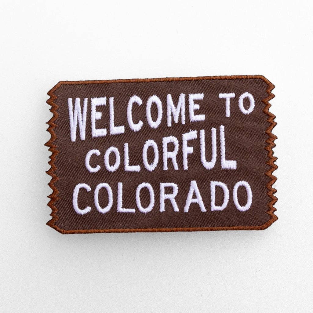 Flat on white, the brown Welcome to Colorful Colorado patch shows white lettering and a zigzag border.