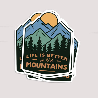 Three Life Is Better In The Mountains stickers fanned in a stack on a pale grey backdrop.