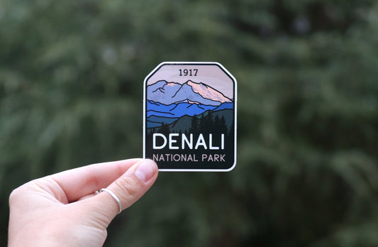 Pulled back a little, the Denali National Park sticker shows its 1917 date and snowy peaks over blurred pines.