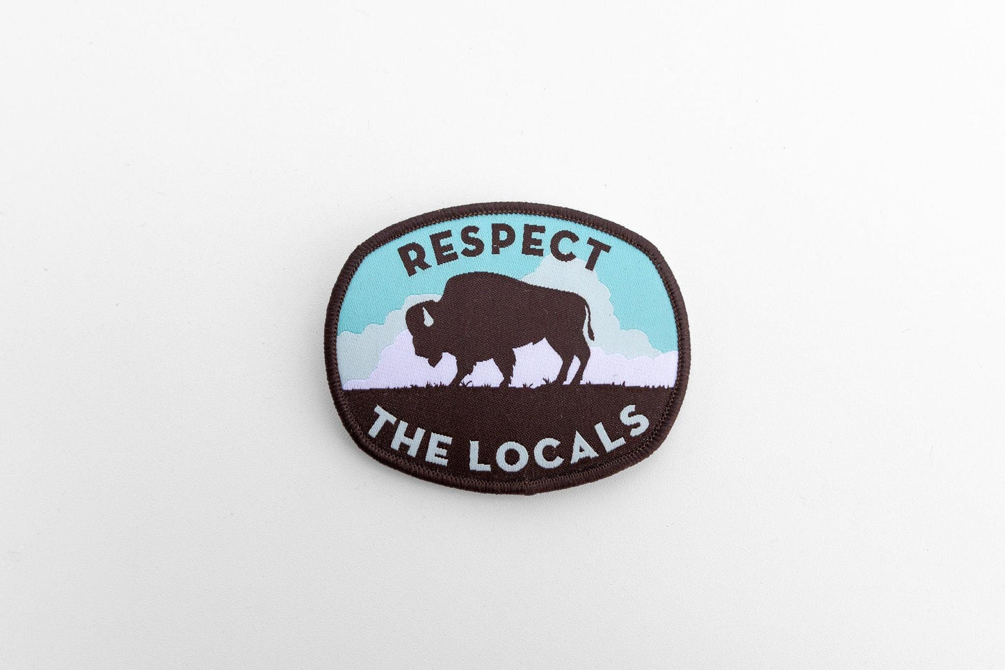 Set small in the frame on a plain white surface, the Respect The Locals bison patch sits slightly angled.