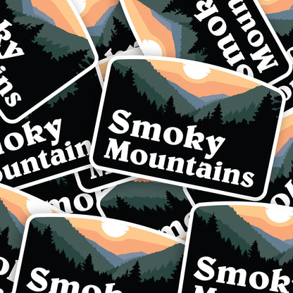 A pile of Smoky Mountains stickers overlaps at different angles, repeating the sunset ridge design.