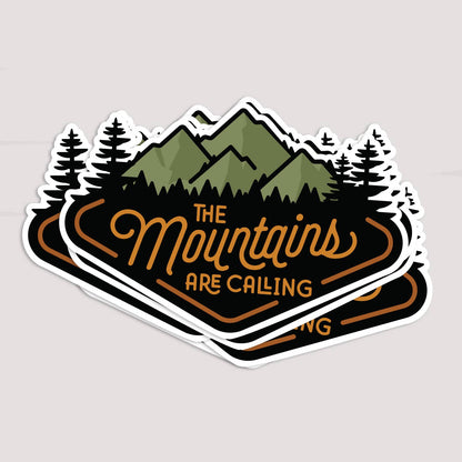 A small stack of The Mountains Are Calling stickers fans out on a pale surface.