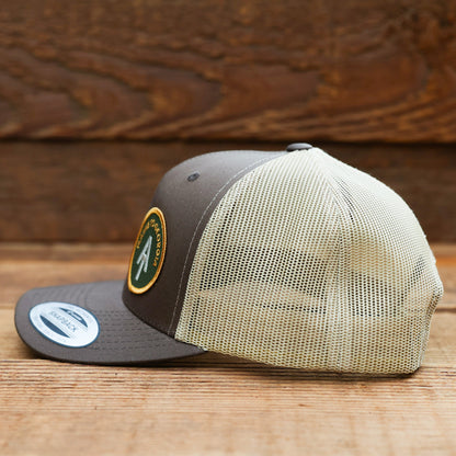 Profile view of the brown Appalachian Trail trucker hat, deep mesh side filling the frame over old wood.