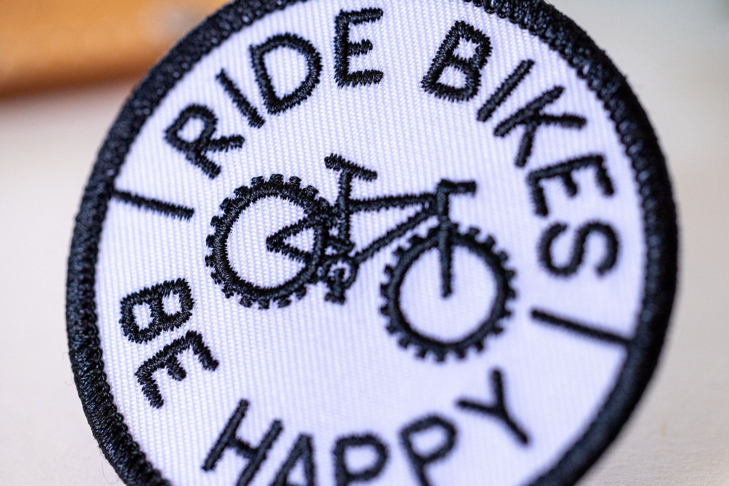 Tilted close enough to count the stitches, the Ride Bikes Be Happy patch fills the frame with its bike.