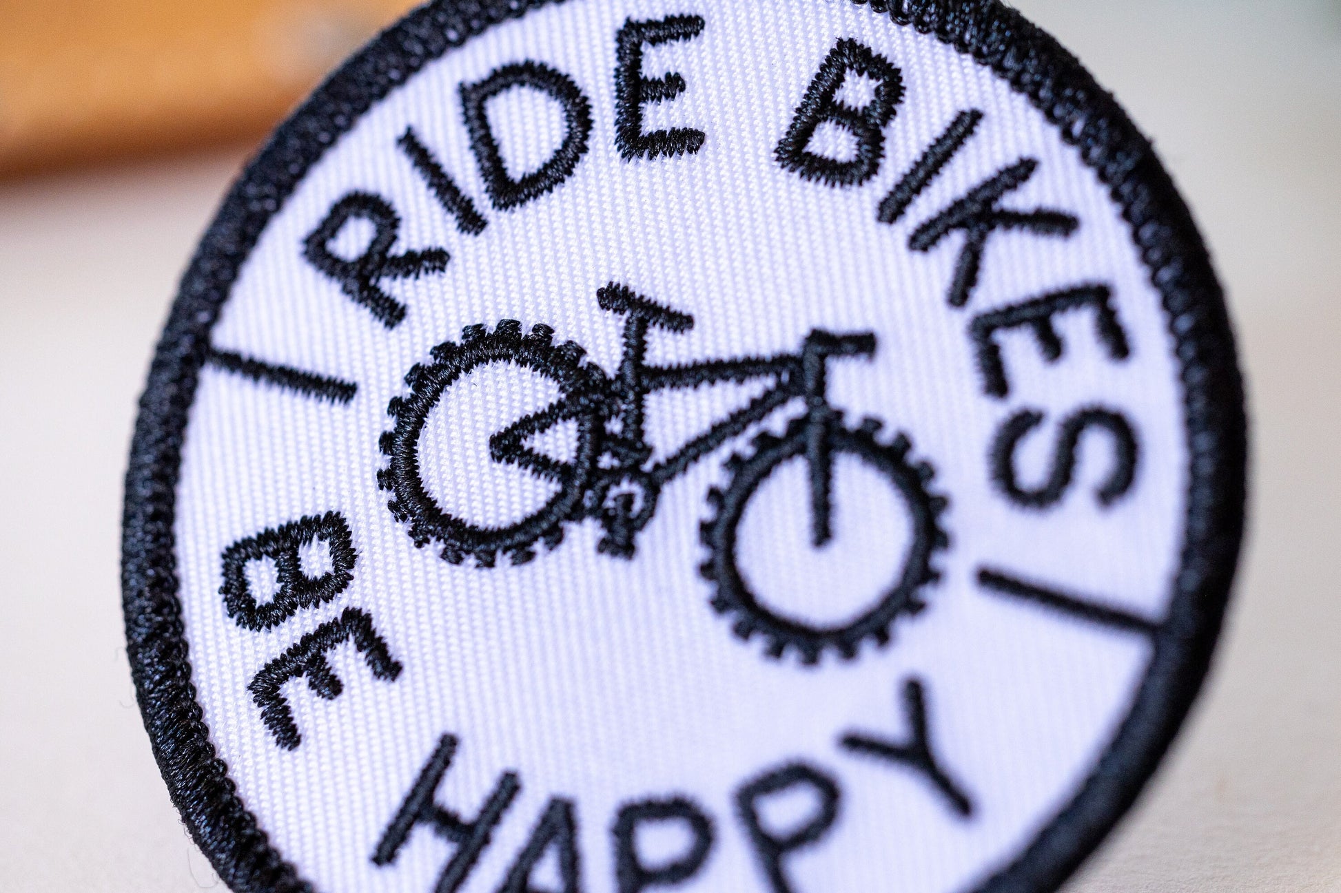 Tilted close enough to count the stitches, the Ride Bikes Be Happy patch fills the frame with its bike.