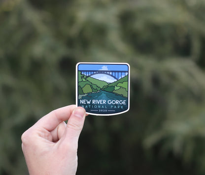Held further back against evergreen branches, the New River Gorge National Park sticker shows its 2020 date.