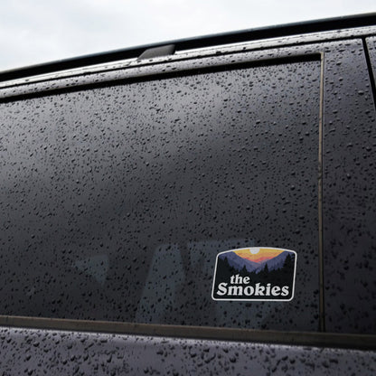 Raindrops cover a dark truck window where the The Smokies sticker sits applied near the frame.