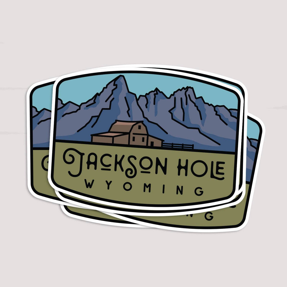 Two Jackson Hole Wyoming stickers overlap in a loose stack, the top one covering most of the one beneath.