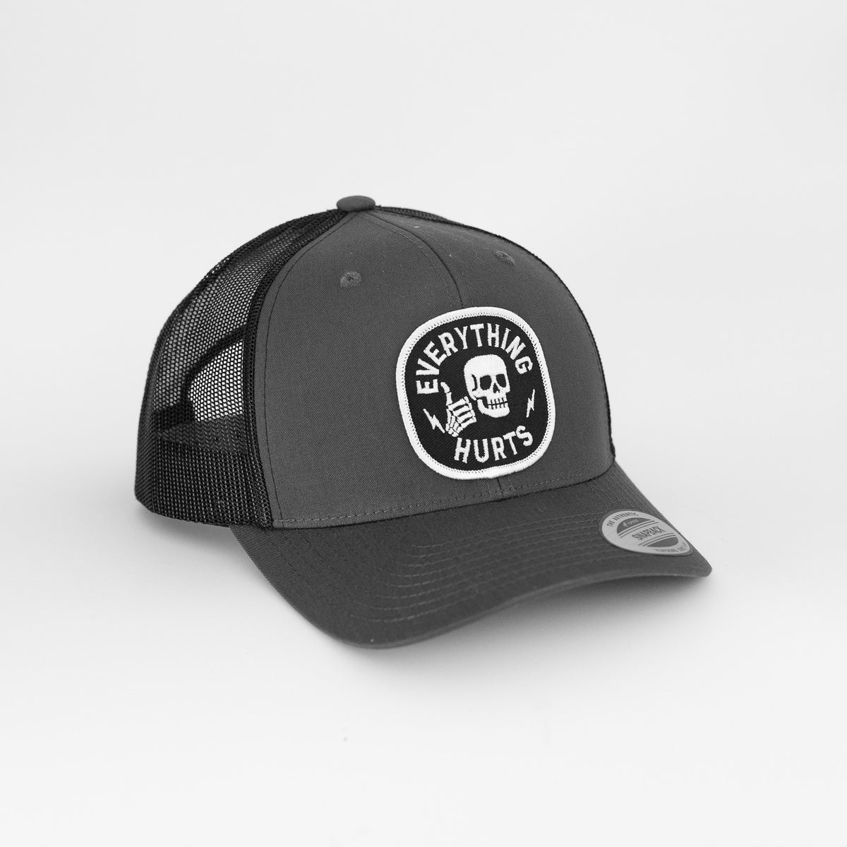 Against a plain white background, the grey Everything Hurts trucker hat shows its black mesh back and skull patch.