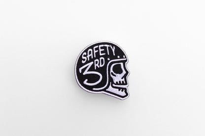 Small against a wide white background, the Safety 3rd Helmet Patch sits alone with its skull facing right.