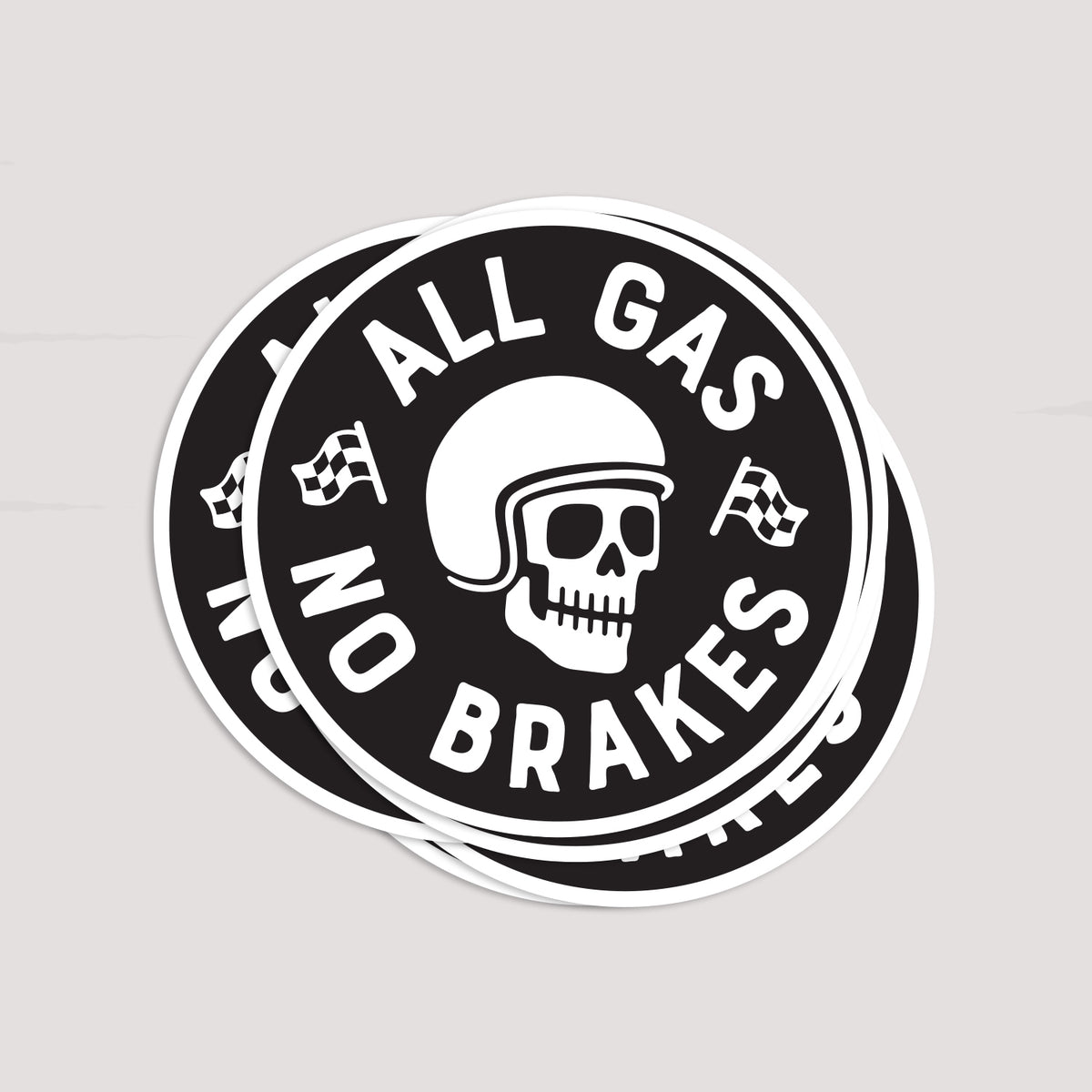 A small stack of All Gas No Brakes stickers sits slightly offset, their white borders layered against pale grey.
