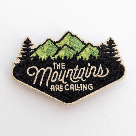 Close and square on, the embroidery of The Mountains Are Calling patch shows every raised thread and pine.