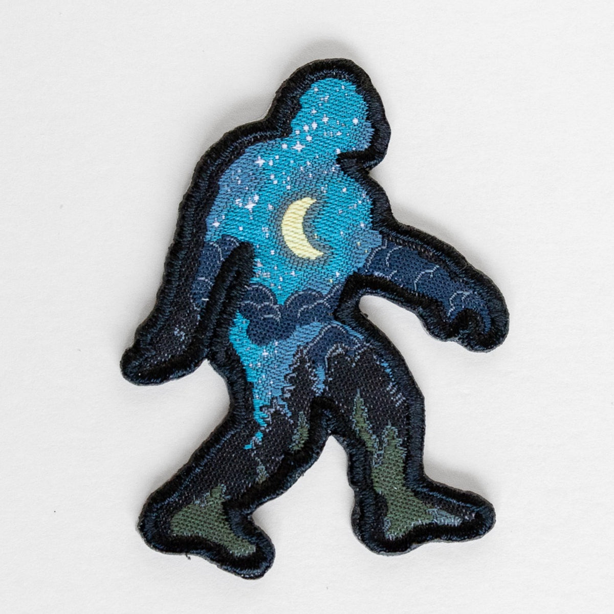 Against a plain grey backdrop, the Bigfoot Night Sky Patch shows a walking silhouette filled with stars and a crescent moon.