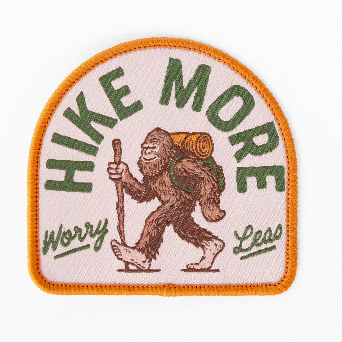 Flat against a white background, the Hike More Worry Less patch shows Bigfoot walking with a backpack and hiking stick.