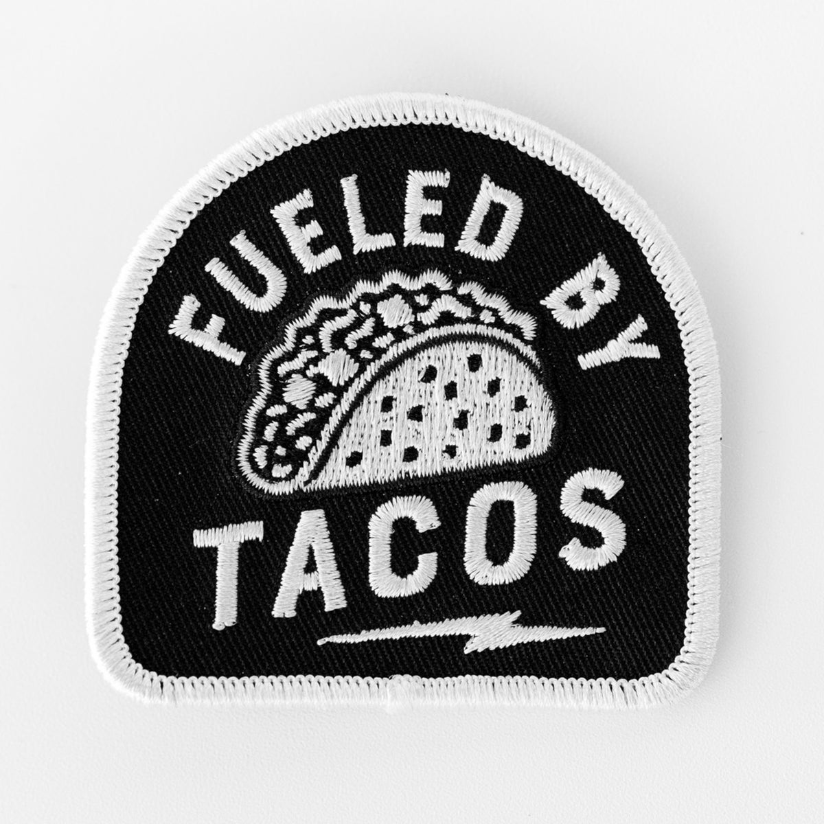On a plain white background, the Fueled By Tacos patch shows an embroidered taco above a small lightning bolt.