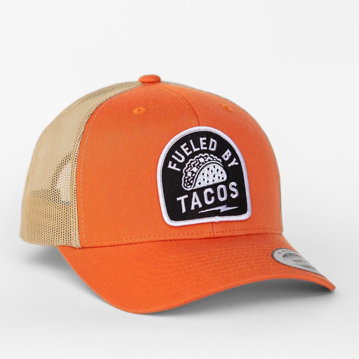 An orange front panel meets tan mesh on this Fueled By Tacos trucker hat, the taco patch stitched above the brim.