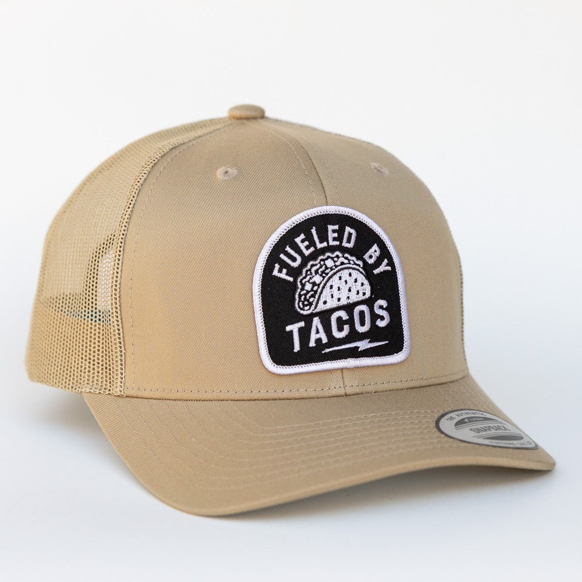 A tan on tan colorway gives this Fueled By Tacos trucker hat a quieter look with the same embroidered taco patch.